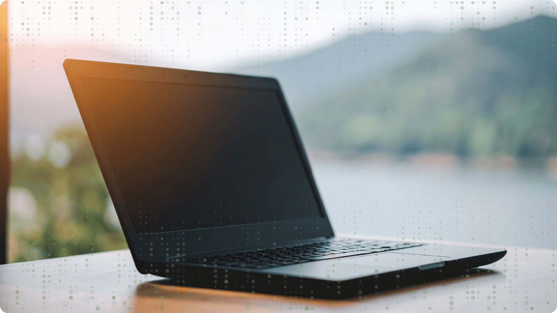 A computer sitting on a desk, mountain view window in the background, decorative dots in foreground