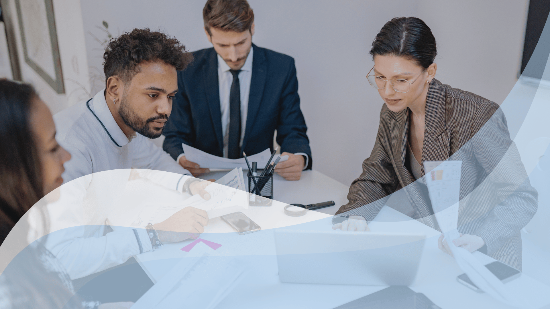 Group working at a table and referencing a computer, with blue and white abstract waves overlaid on image